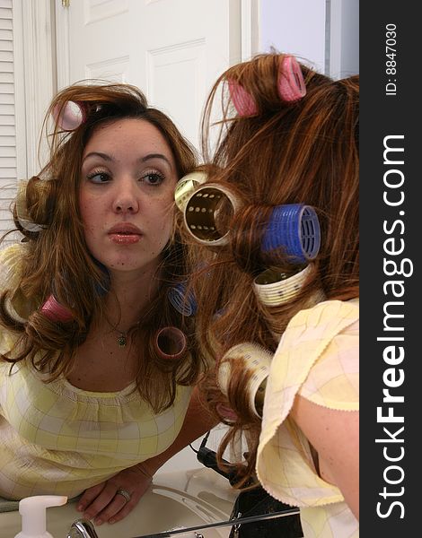 Sexy woman model with curlers in hair gets ready for her photo shoot, checking makeup in the mirror. Sexy woman model with curlers in hair gets ready for her photo shoot, checking makeup in the mirror
