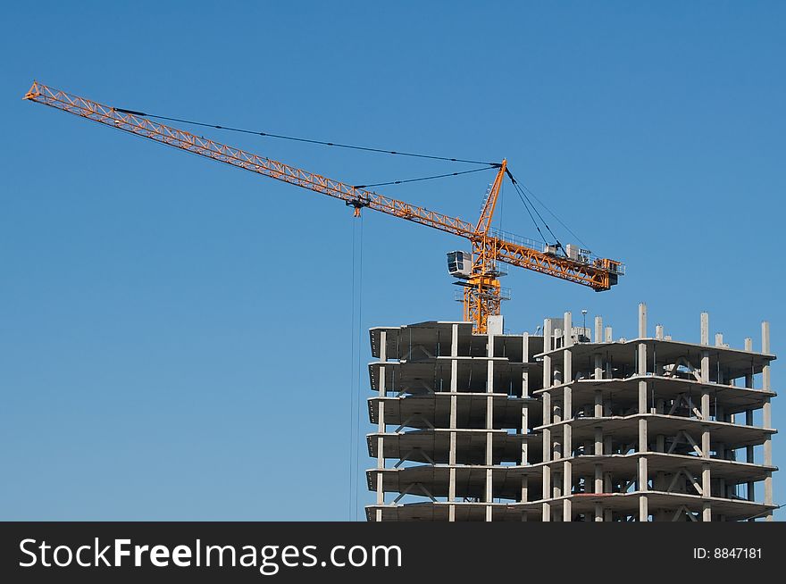 The elevating crane on clear blue sky background and building