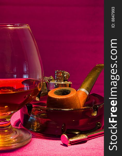 Glass of whiskey, pipe and ashtray arranged close up. Glass of whiskey, pipe and ashtray arranged close up