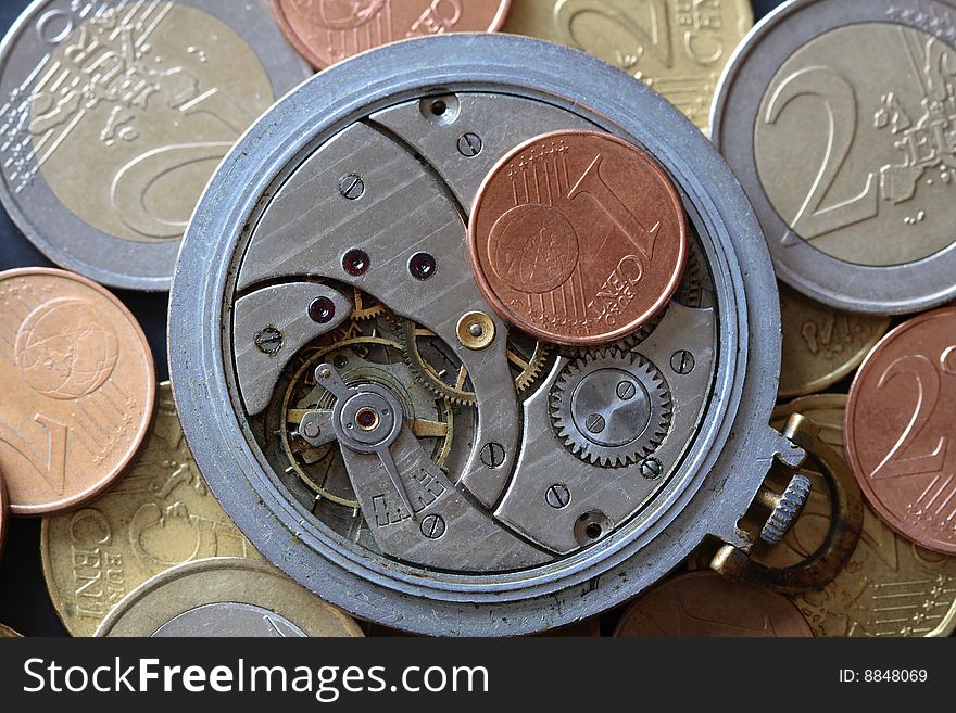 Opened watch mechanism lying on european coins background. Opened watch mechanism lying on european coins background