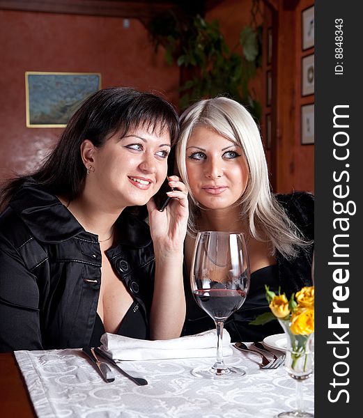 Two young women listen to a conversation on the phone