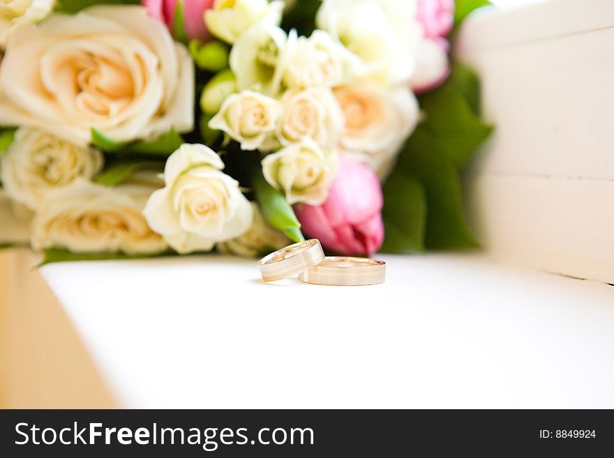 Two wedding rings behind flowers