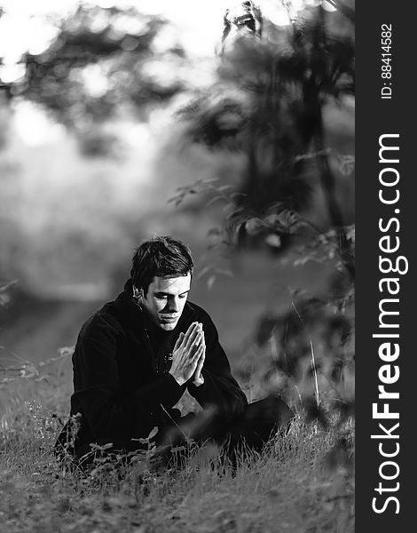 Grayscale Photography of Man Sitting on Grass Field