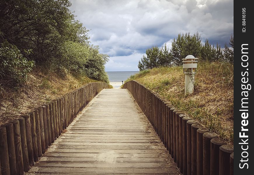 Straight wooden boardwalk leading to beach in distance.