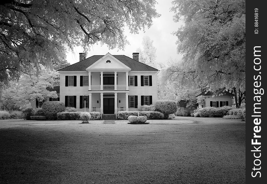 A black and white photo of a modern stylish house with a garden and a lawn. A black and white photo of a modern stylish house with a garden and a lawn.