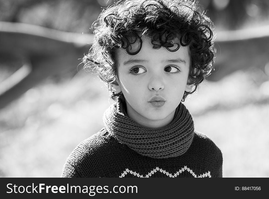 A black and white portrait of a child with curly hair.