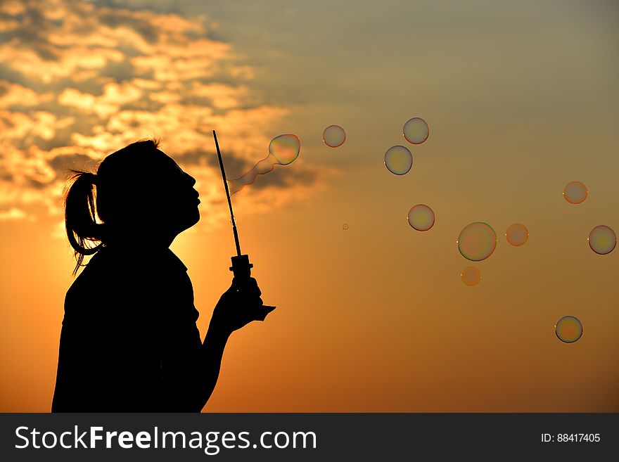 A girl blowing soap bubbles at sunset. A girl blowing soap bubbles at sunset.