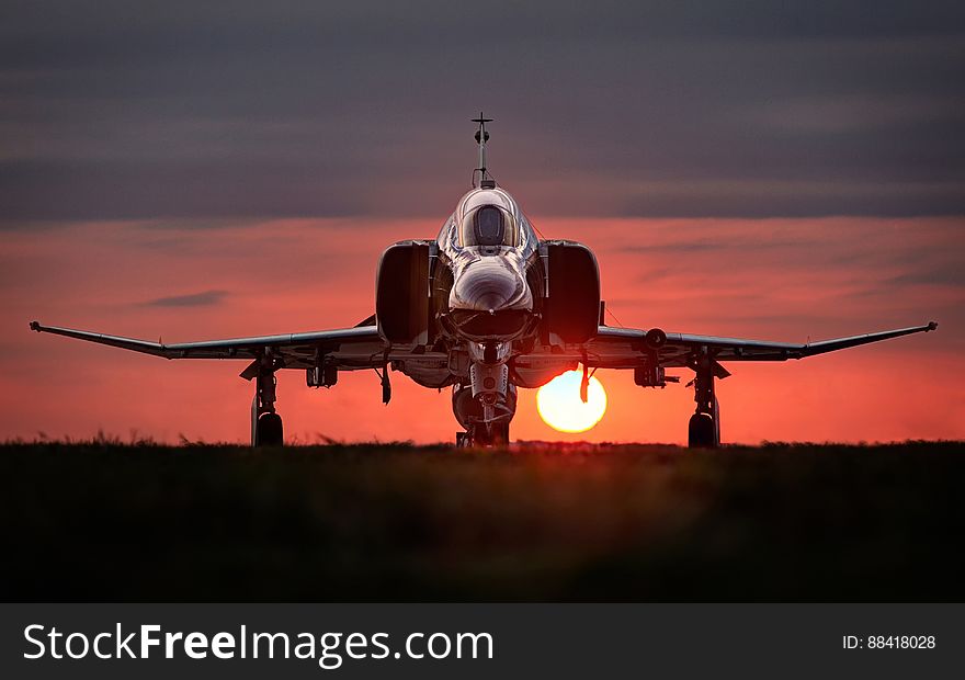 Front view of military jet aircraft on runway with orange sunset background. Front view of military jet aircraft on runway with orange sunset background.