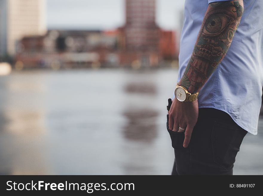 A man with tattoos standing next to water.