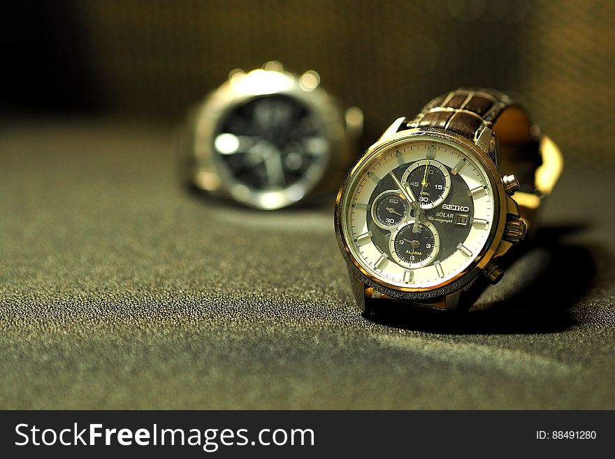 Two men's wristwatches on table surface. Two men's wristwatches on table surface.