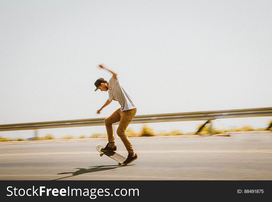 Young male skateboarder performing trick on asphalt road. Young male skateboarder performing trick on asphalt road.