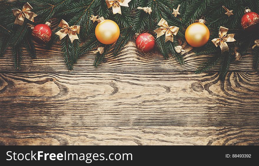 A Christmas background with baubles and conifer branches on wood background.