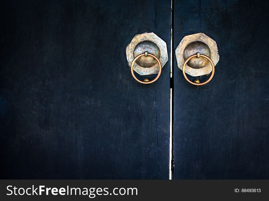 A pair of antique doors with brass pull handles.