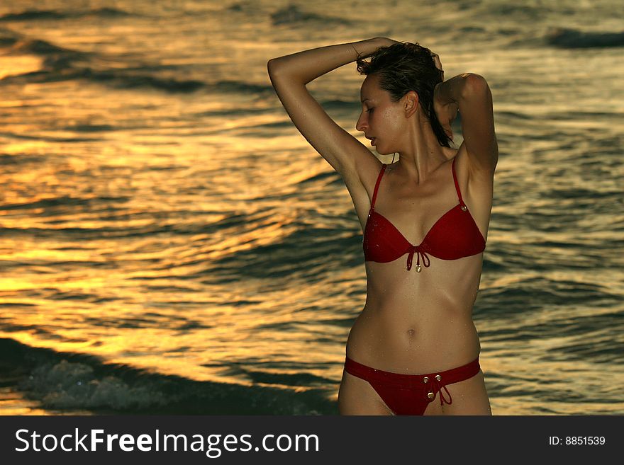 Woman in red bikinis on the beach by sunset. Woman in red bikinis on the beach by sunset