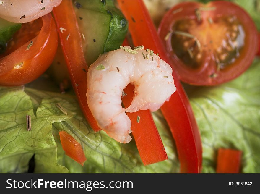 Fresh vegetables salad with shrimps on the black dish.