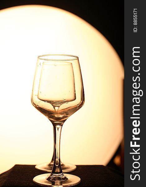 Two glasses in a row. Yellow background, dark floor. Artistic picture. Two glasses in a row. Yellow background, dark floor. Artistic picture