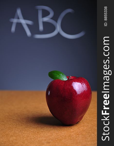 Red apple on table and blackboard with ABC letters. Red apple on table and blackboard with ABC letters