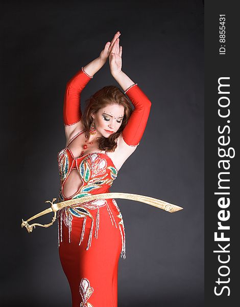 Belly Dancer in red costume balancing a tribal sword. Belly Dancer in red costume balancing a tribal sword