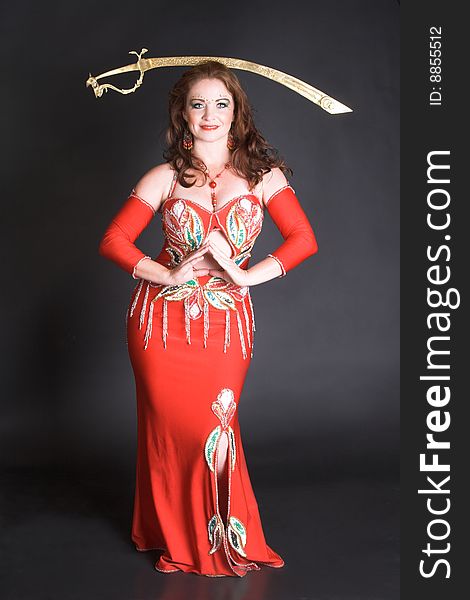 Belly Dancer in red costume balancing a tribal sword. Belly Dancer in red costume balancing a tribal sword