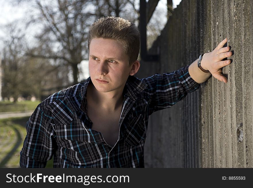 Young man is bases about the concrete wall. Young man is bases about the concrete wall