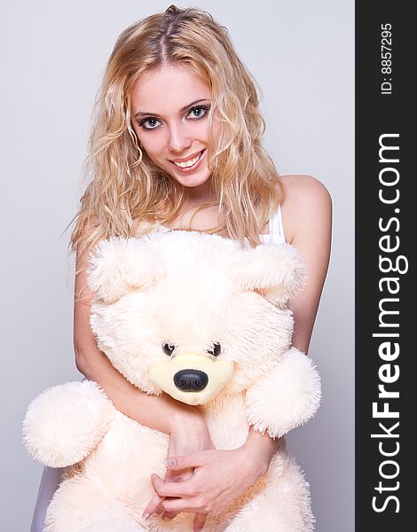 Beautiful girl with a teddy bear on a gray background