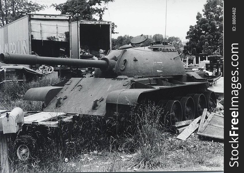 Black and white photo of an old, retired tank in a junkyard.