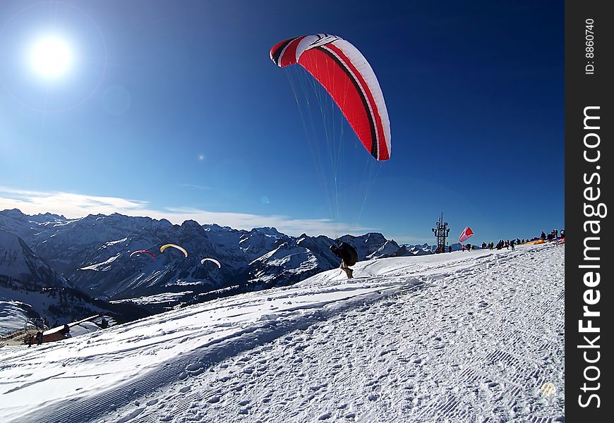 Paraglider taking off from a snowy hill. Paraglider taking off from a snowy hill