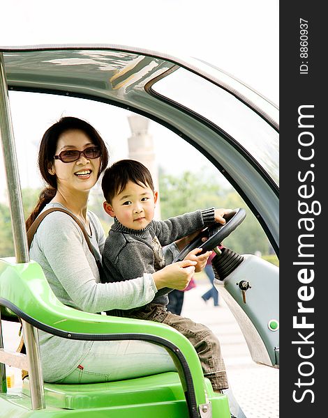 A picture of a little chinese boy and his mother driving electromotor together and having great fun. A picture of a little chinese boy and his mother driving electromotor together and having great fun