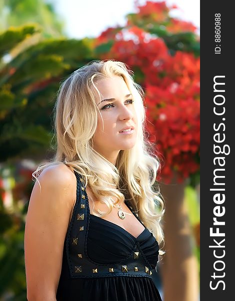 Beautiful blonde girl in black dress in summer garden