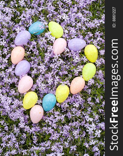 Pastel colored Easter Eggs in a heart shape on a background of fresh purple Phlox blooms. Pastel colored Easter Eggs in a heart shape on a background of fresh purple Phlox blooms