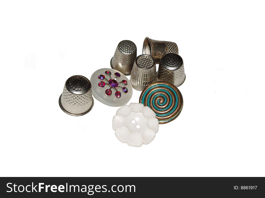 Vintage metal thimbles and vintage buttons against a white background. Vintage metal thimbles and vintage buttons against a white background