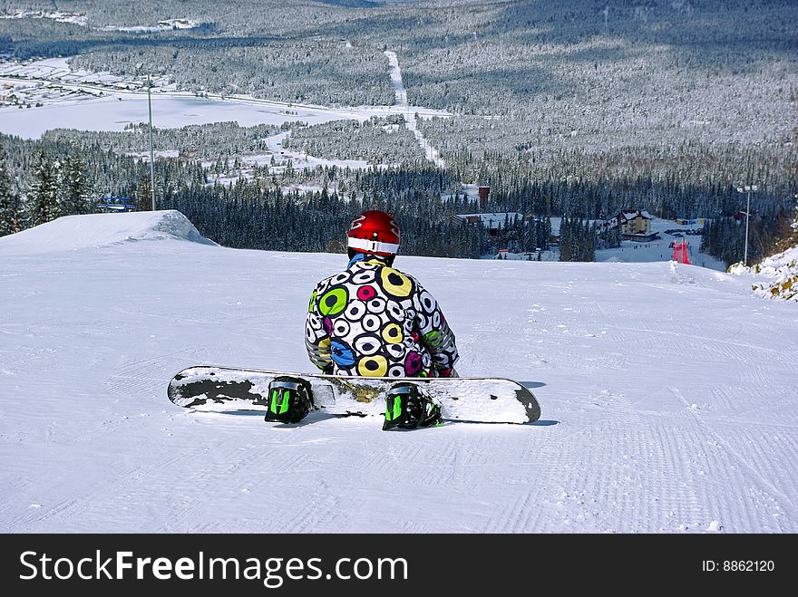 Sitting snowboarder on slope - winter sport scene