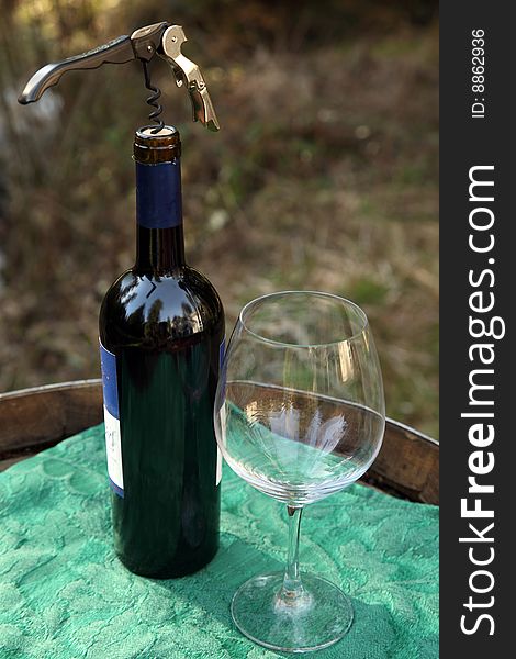Single isolated Wine bottle, corkscew and glass outdoors in nature scene