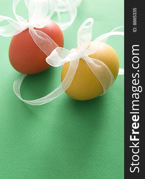 Red & yellow egg with transparent ribbon on green background