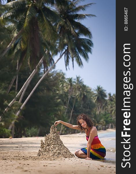 A woman building a sandcastle on the beach.