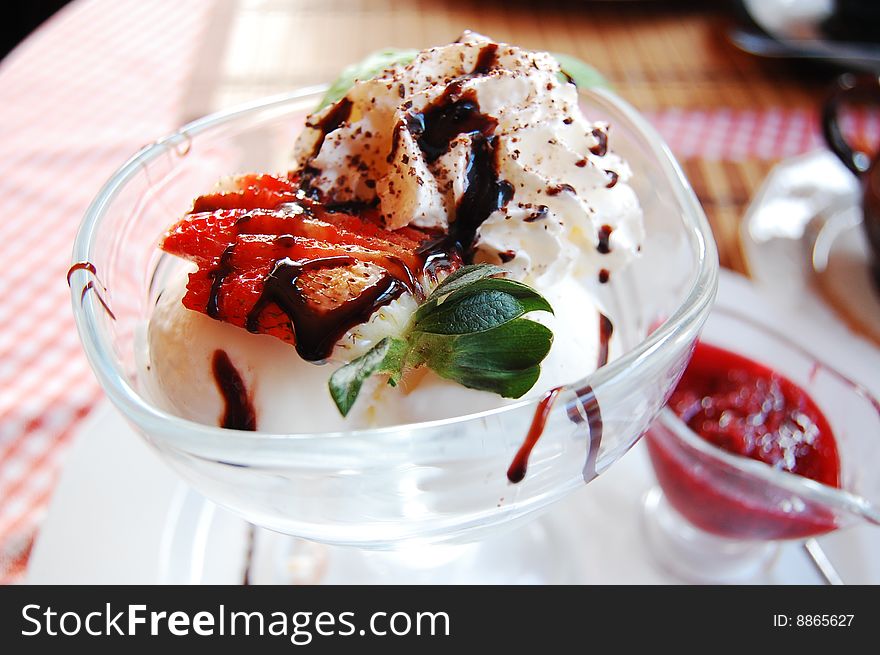 Vanilla ice-cream and hot raspberries dessert served with a strawberry and liquid chocolate.