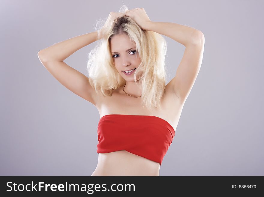 Beautiful sexy blond in red standing isolated on grey background. Beautiful sexy blond in red standing isolated on grey background