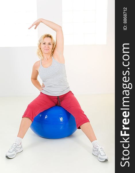 Elder woman dressed sportswear exercising with fitness ball. She's looking at camera. Elder woman dressed sportswear exercising with fitness ball. She's looking at camera.