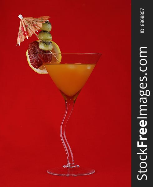 Tropical cocktail with slices of fruit on a red background. Tropical cocktail with slices of fruit on a red background