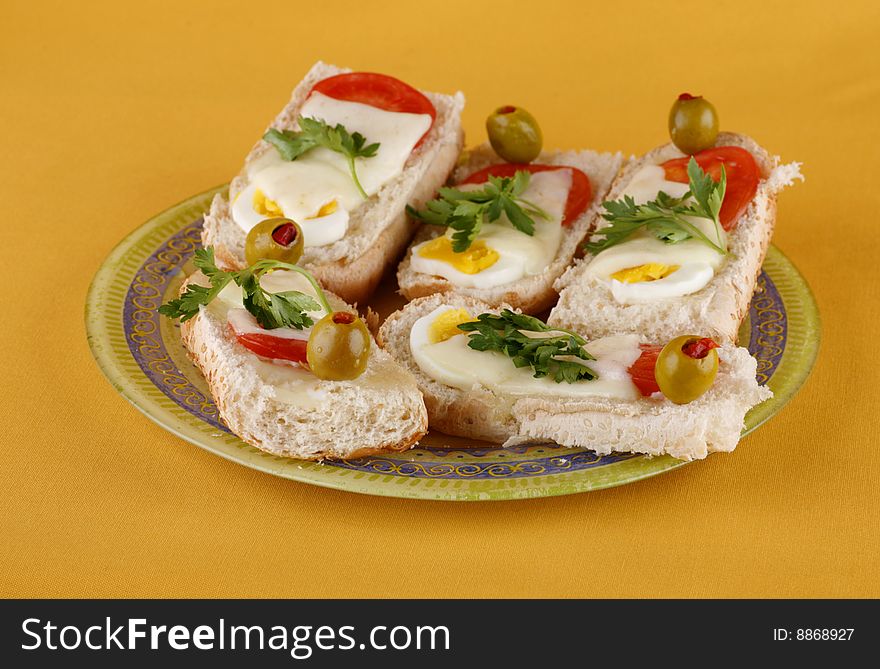 Hot sandwiches with egg, a tomato, cheese and olives on the yellow