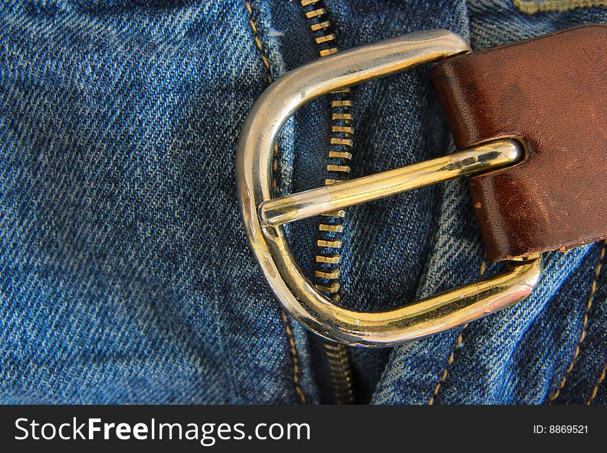 Detail of the metal buckle on blue jeans