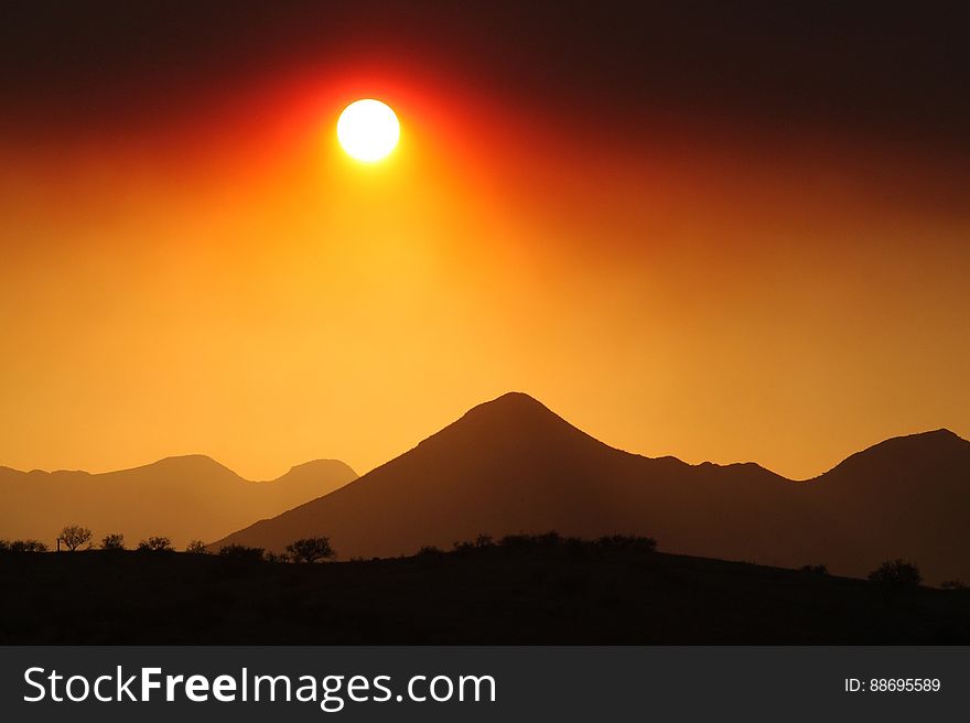 The sun above the dark silhouettes of hills. The sun above the dark silhouettes of hills.