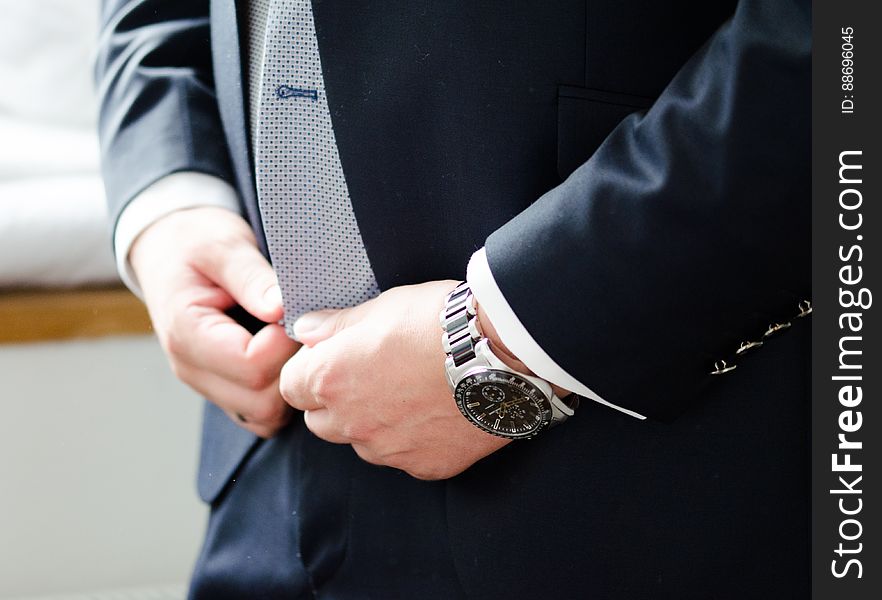 A close up of groom`s hands buttoning the tuxedo. A close up of groom`s hands buttoning the tuxedo.
