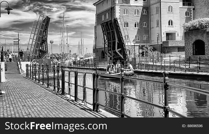 A black and white photo of a promenade and a canal in an old town. A black and white photo of a promenade and a canal in an old town.
