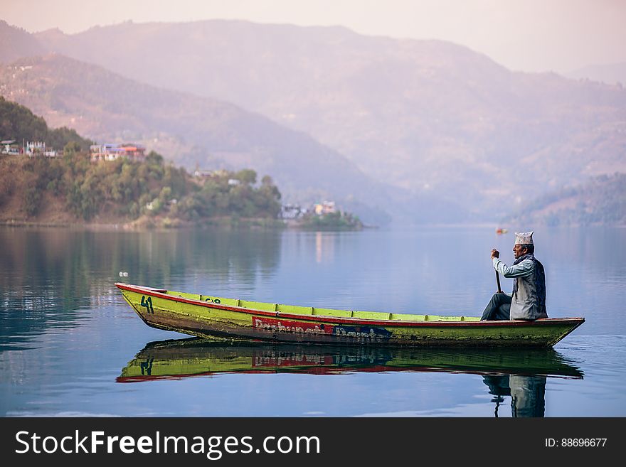 An old fisherman in a boat on a lake. An old fisherman in a boat on a lake.