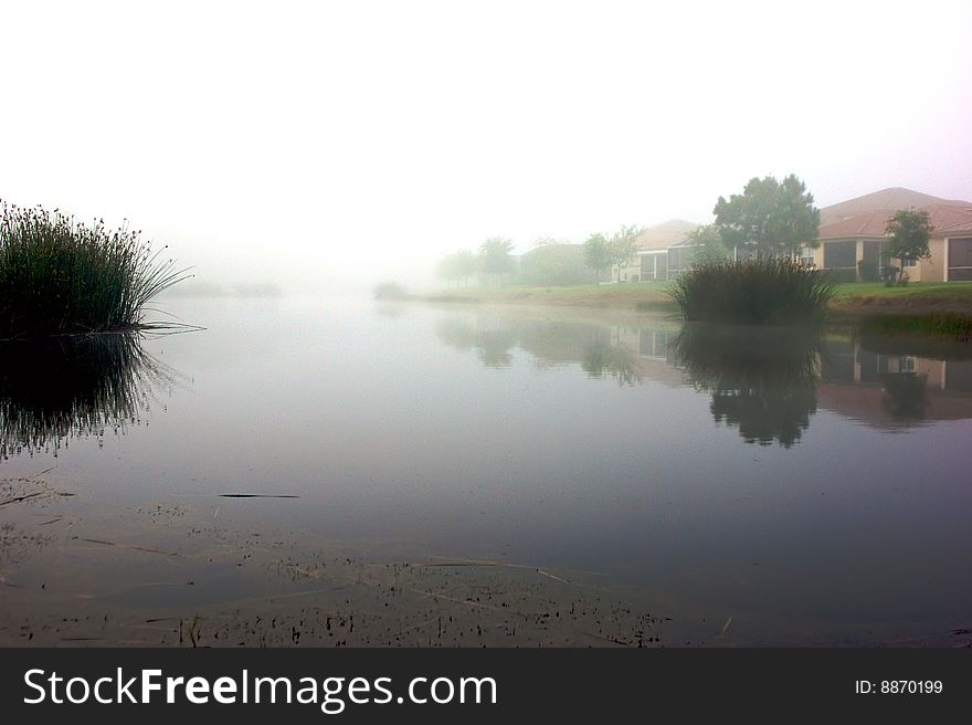 Foggy morning in florida showing lake front homes reflected in water fading off into the distance. Foggy morning in florida showing lake front homes reflected in water fading off into the distance