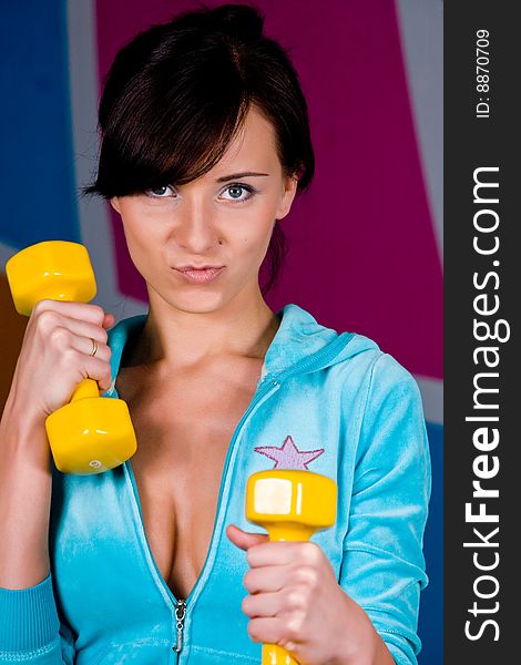Funny woman curls dumbbells with a happy smile