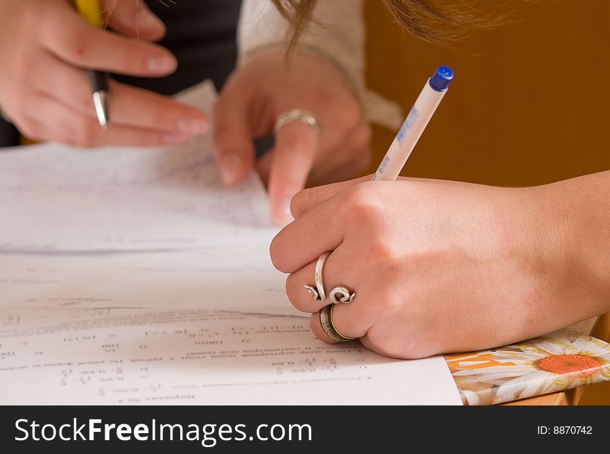 Hands of two young women writing behind one table. Hands of two young women writing behind one table.