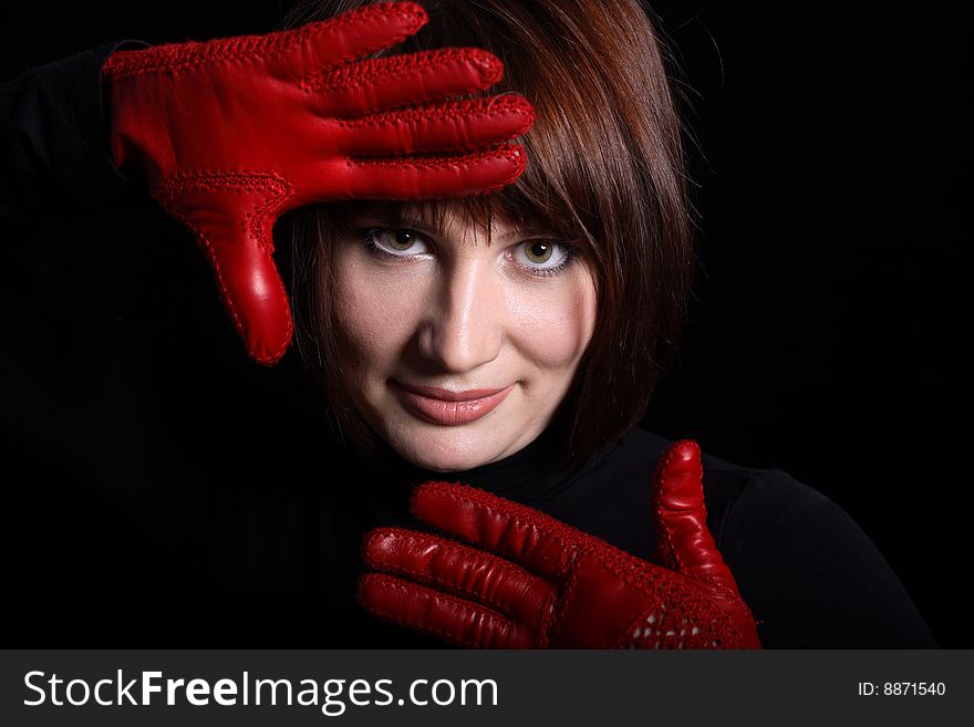 Woman looking straight from dark. In front of her red gloves on her hands. Horizontal