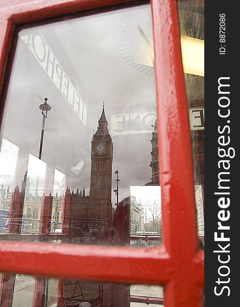 A reflection of the big ben in a classic english red phone booth in London